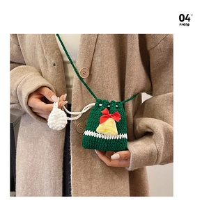 Detail of hand-knitted green Christmas reindeer bag with yellow bell and red bow buckle