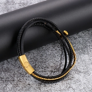 Detail of multi-layer black braided leather bracelet with golden anchor and magnetic clasp