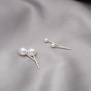 Macro shot of elegant white pearls on silver needles resting on gray silk fabric