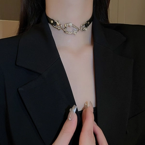 Détail d'un choker en cuir noir avec chaîne argentée irrégulière et perle