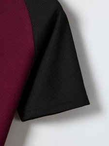 Dettaglio macro del top maschile in maglia a nido d'ape bordeaux e polsino nero della manica