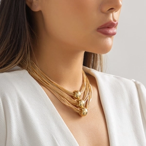 Detailed view of layered gold punk chain necklace featuring geometric spherical beads on model