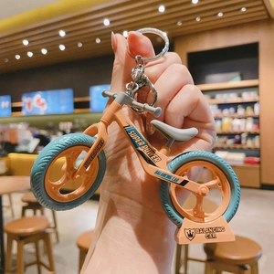 Detail of an orange mini balancing car keychain with Super Power text and display stand