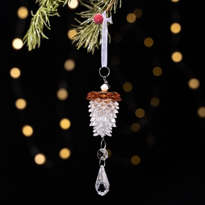 Macro shot of brown acrylic crystal pinecone ornament with faceted droplet on pine branch
