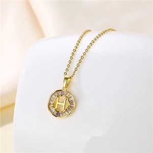 Macro shot of gold 18K plated necklace with letter H pendant and cubic zirconia
