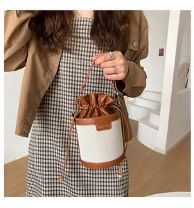 Detail of vintage bucket bag with canvas stitching and brown leather handle on model