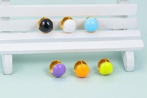 Close-up of bohemian colorful heart enamel hoop earrings on mini chair display
