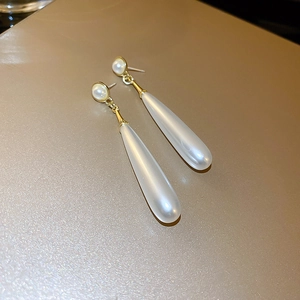Detailed view of elegant drop earrings featuring white pearls and gold metal links