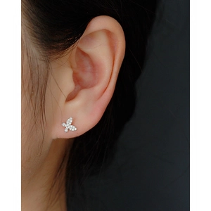 Close-up of a silver butterfly earring with colorful zircon crystals on a female model
