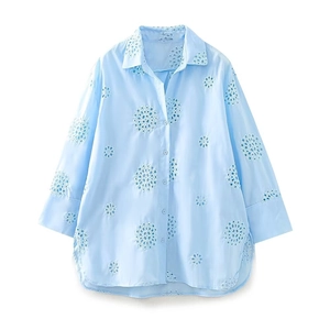 Camicia azzurra a maniche lunghe con ricamo traforato su sfondo bianco neutro