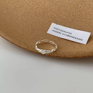 Silver heart chain ring detail on a minimalist wooden tray with soft lighting