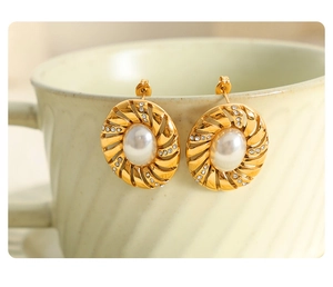 Gros plan sur des boucles d'oreilles spirales dorées avec perles et strass brillants