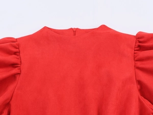 Détail de robe rouge en suédine à col rond et manches bouffantes avec fermeture éclair cachée
