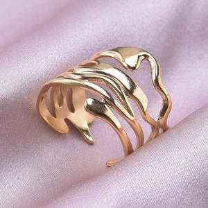 Detailed close-up of golden multi-layered wave ring on elegant pink silk fabric