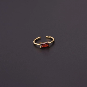Close-up of golden adjustable ring with red rectangular gemstone and beaded band texture