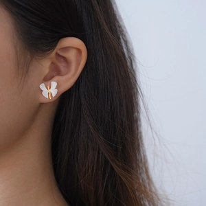 Close-up of S925 silver butterfly earrings with gold accents on the model ear