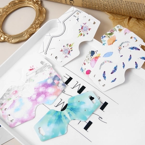 Artistic jewelry display cards with feather and marble patterns on a vintage tray