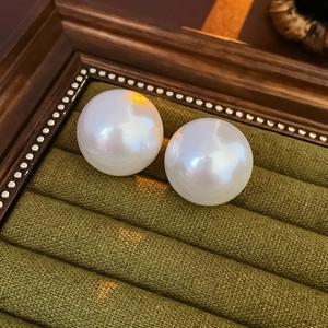 Macro shot of elegant round white pearls on dark green velvet tray with vintage wood
