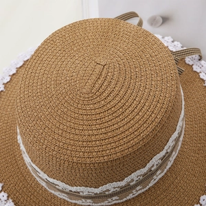 Close-up of woven straw sun hat featuring white lace trim and checkered bow ribbon