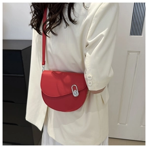 Detail of red leather saddle bag showing silver oval metal buckle and fine texture