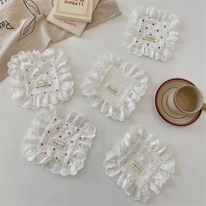 Detail of five cotton lace coasters with heart embroidery and scalloped edges
