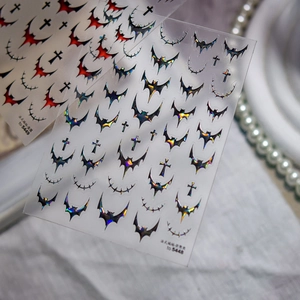 Close-up of gothic nail stickers with metallic red and aurora laser bat designs