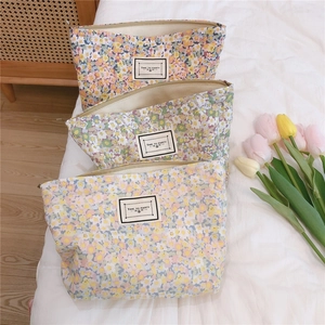 Detail of floral canvas pouches with zipper closure and retro fabric labels on a bed
