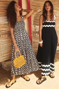 Close-up of elegant summer maxi dresses with black and white wavy patterns and woven bag
