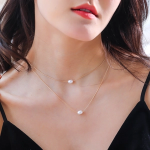 Detail of minimalist double-layered gold necklace with two white pearls on a model