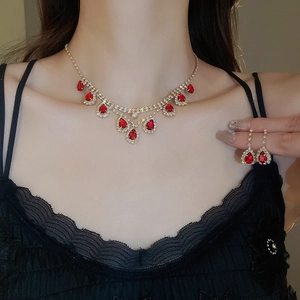 Elegant gold necklace and earrings set featuring red teardrop stones and crystals on model
