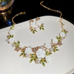 Detail of floral jewelry set featuring white roses with green leaves and pearls