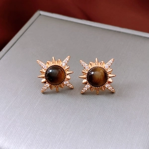 Detailed macro view of 18K gold starburst earrings featuring brown tiger eye gemstones