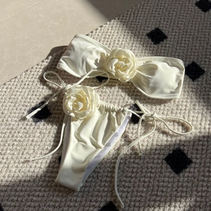 Creamy white bikini set with 3D rose accents on bandeau top and side-tie bottoms