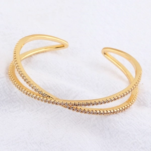 Detailed close-up of double-layer crisscross gold bracelet with white cubic zirconia pavé