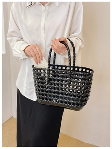Close-up of black hollow woven jelly basket bag held by model for summer beach vacations