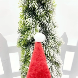 Close-up of mini red Christmas lollipop hat with white pompom on a snowy tree background