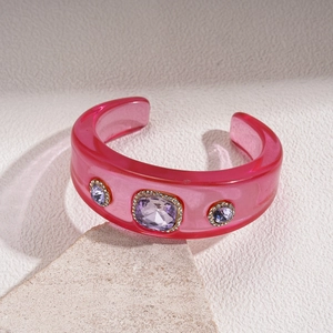 Detail of pink resin open bangle featuring purple gemstone inlay and crystal bezel
