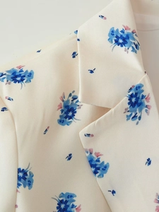 Close-up of beige floral suit jacket featuring a classic collar and blue flower pattern