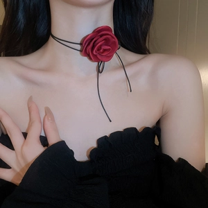 Detail view of a handcrafted black fabric choker with a large red rose and hanging cords