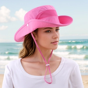 Pink sun hat with breathable mesh side and adjustable chin strap on a sunny beach