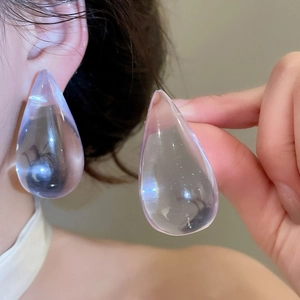 Close-up macro view of transparent purple teardrop shaped acrylic earrings worn by model