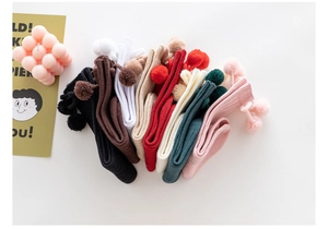 Flat lay of colorful ribbed baby knee high socks with cute pom-pom details and soft texture