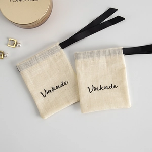 Detail of beige linen drawstring pouches with black ribbons and Vinknde branding