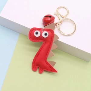 Close-up of red leather dinosaur keychain with golden ring and matching red bell charm