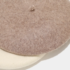 Close-up of wool felt texture on brown and beige berets with classic top tail detail