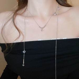 Détail macro du collier long argenté multicouche avec pendentifs en cristal et perles