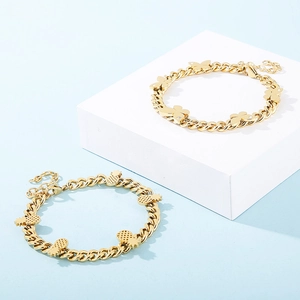 Detailed view of gold butterfly and pineapple pendant bracelets on display blocks