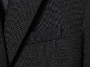 Detail of notched lapel and flap chest pocket on black twill fabric suit jacket