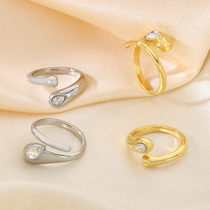 Detail of four gold and silver snake rings with teardrop gems on soft silk fabric