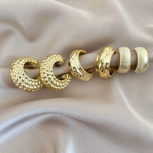 Detailed view of three gold C-shaped earrings with dot, smooth, and striped textures